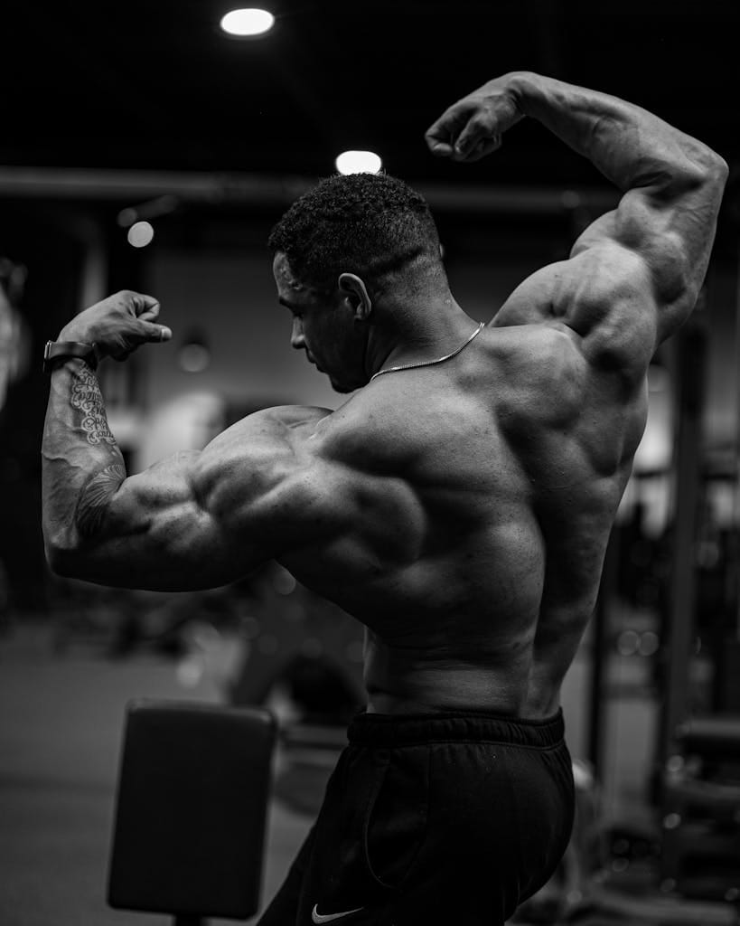 Black and white photo of a bodybuilder flexing muscles indoors. | Unlock HUGE Gains: This is The ONLY Pull Workout You'll Ever Need for Massive Muscle