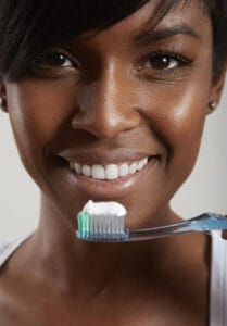 black woman brushing her teeth | STOP RINSING! Dentists Reveal Why You're Washing Away Cavity Protection