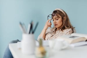 Caucasian woman looks exhausted while taking a break with eyes closed at her desk. | Tired All the Time? This Powerhouse Supplement Boosts Focus, Stamina & Overall Vitality