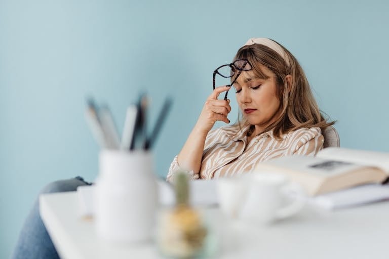 Caucasian woman looks exhausted while taking a break with eyes closed at her desk. | Always Tired? The Vitamin Deficiency Most Adults Have That Steals Your Energy (And How to Fix It!) | Brain Fog Breakthrough: The SHOCKING B12 Deficiency Link Doctors Say Is Stealing Your Memory!