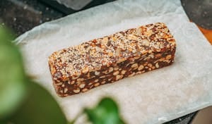 Close-up image of a nut and sesame seed protein bar on parchment paper, ideal for healthy snacking. | Stop Cravings Cold! The 10 "Clean" Protein Bars That Actually Keep You Full (Trainer Approved!)