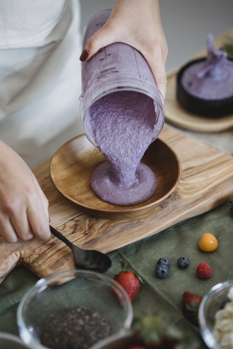 Close-up of a berry smoothie being poured into a wooden bowl, surrounded by fresh ingredients. | Hate Protein Powder? 10 Genius Ways to Make Your Smoothies a Protein Powerhouse (Naturally!)