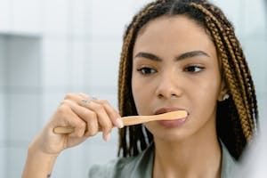 Close-up of a woman with braided hair brushing her teeth, highlighting oral hygiene. | Think Your Toothpaste is Safe? The Shocking Ingredient You're Brushing With Daily