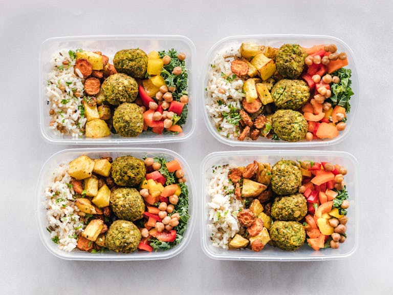 Colorful meal prep containers with falafel, chickpeas, rice, and vegetables for a healthy lifestyle. | Stop Wasting Time: 15 Diet Secrets That Burn Belly Fat 3x Faster in 30 Days