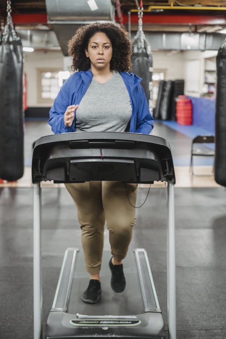 Full body of overweight female running on treadmill during workout and looking at camera | Reclaim Your Power: The Gentle Walking Plan for Plus-Size Bodies (Boost Energy & Shed Pounds Effortlessly!)