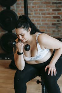 Plus-size woman intensely lifting dumbbell in a gym, showcasing strength and dedication. | Your Body, Your Rules: Simple Strength Training for Plus-Size Beginners (Build Muscle, Boost Metabolism & Thrive!)