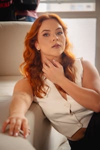 Young woman with red hair sitting thoughtfully indoors, showcasing modern style. | The Simple Morning Routine That Reduced Wrinkles and Boosted Energy in 3 Weeks