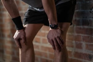 A close-up of an athlete resting after exercise, wearing a digital fitness watch. | Why Your Legs Aren't Growing: A Trainer's Plea to Avoid These 6 Leg Day Traps (Maximize Your Power!)