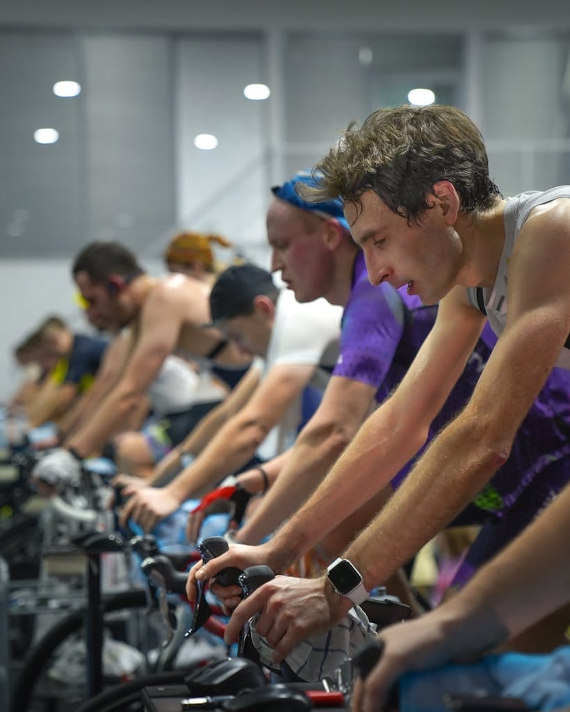 A group of people intensely focused during an indoor cycling class, showcasing fitness and teamwork. | spin class
