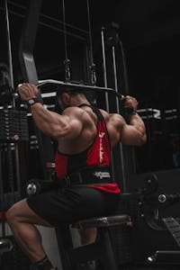 A muscular man doing lat pulldown exercise on a gym machine. | Workout Saboteurs: 10 Popular Exercises That WASTE Your Time (And 10 Powerful Moves For Real Gains!)