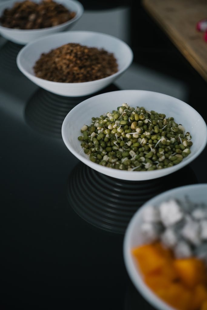 A variety of food bowls featuring mung beans, displayed on a reflective surface. | Protein Powerhouse Carbs? 7 Unexpected Foods That Pack More Protein Than An Egg!