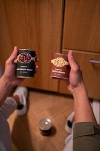 Close-up of hands holding canned red kidney and white beans indoors. | Chef's Secret Pantry: 6 Canned "Must-Buys" & 4 You Should NEVER Touch (Elevate Your Cooking!)