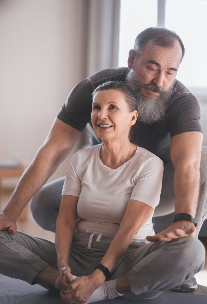 Elderly couple engaging in a yoga session at home, promoting health and happiness. | Women Over 50: Finally Shrink That Stubborn Lower Belly Fat (Expert Strategies Revealed!)