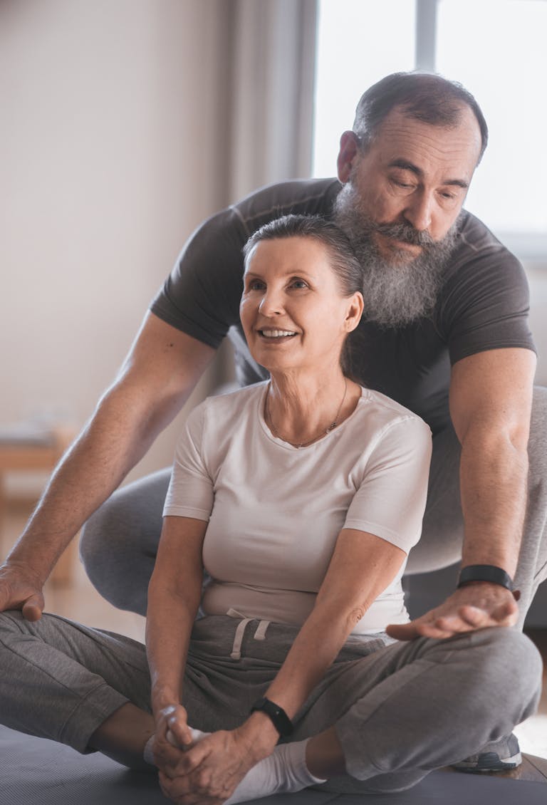 Elderly couple engaging in a yoga session at home, promoting health and happiness. | Women Over 50: Finally Shrink That Stubborn Lower Belly Fat (Expert Strategies Revealed!)