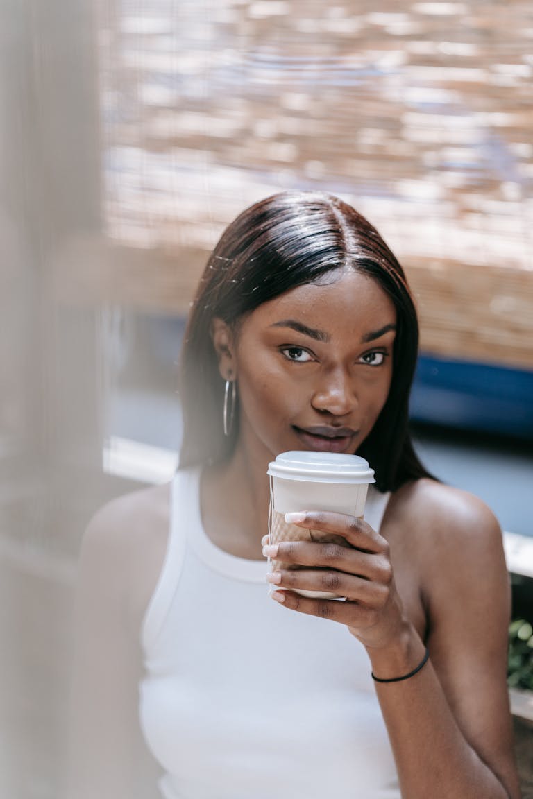 Elegant woman enjoying a coffee outdoors with a charming smile. | Your Coffee Habit for Longevity: Drink It THIS Way to Live Longer (The Secret Revealed!)