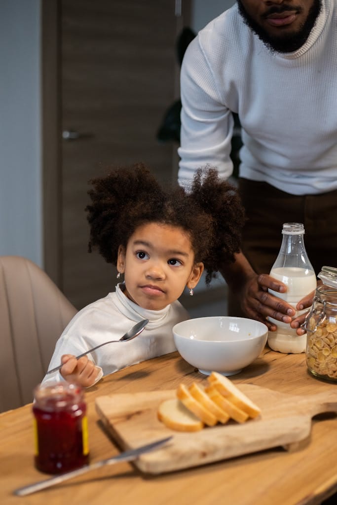 From above of crop African American bearded father and adorable little daughter having breakfast with milk and cornflakes at home | These 10 "Innocent" Everyday Foods Are Secretly Loaded With TOXIC Dyes (You're Eating Them Daily!)