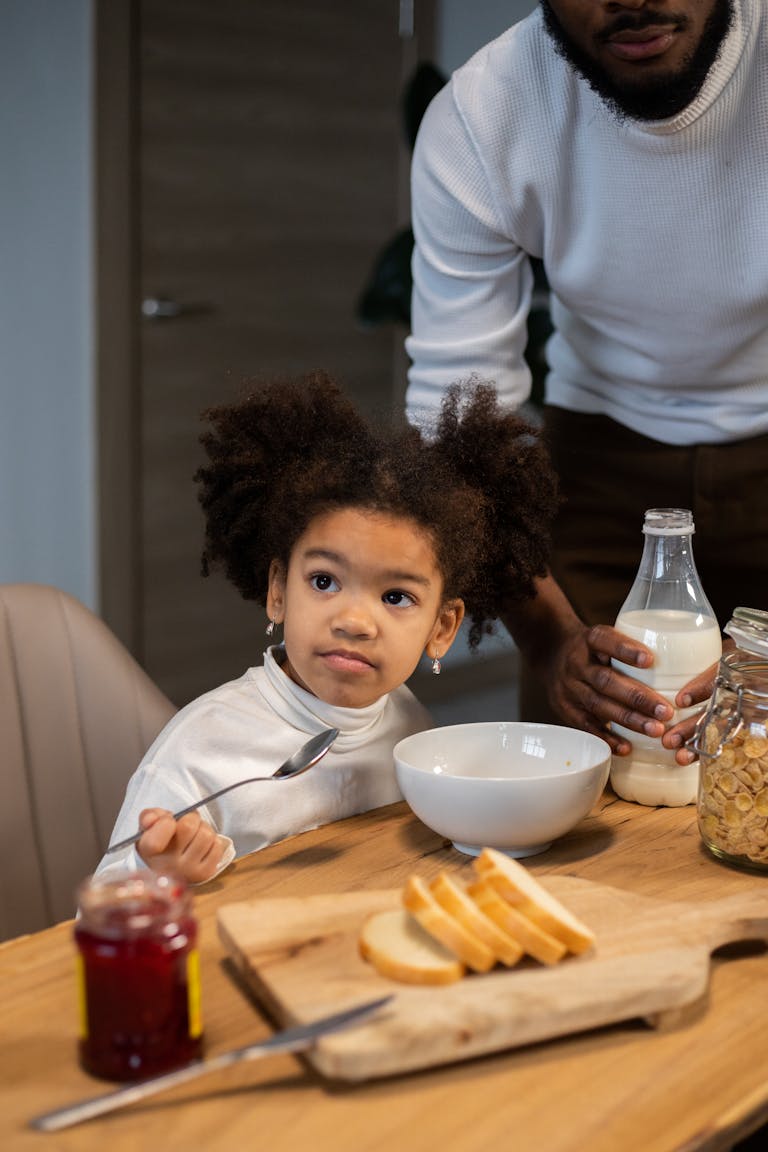 From above of crop African American bearded father and adorable little daughter having breakfast with milk and cornflakes at home | These 10 "Innocent" Everyday Foods Are Secretly Loaded With TOXIC Dyes (You're Eating Them Daily!)