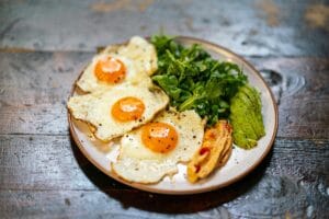 Delicious breakfast plate of fried eggs, arugula salad, and veggies. | Ignite Your Metabolism: Dietitians Reveal The #1 Breakfast for Fat-Burning All Day