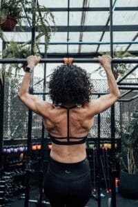 Rear view of a woman working out with pull-ups in a gym, showcasing strength and fitness. | Master Pull-ups & Forge a Monster Back: The 10-Minute Daily Method No One Tells You!