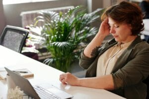 A businesswoman feeling stressed at her home office desk while working on her laptop. | The One Subtle Sign Neurologists Say Is a Major Dementia Warning (Don't Miss This!)