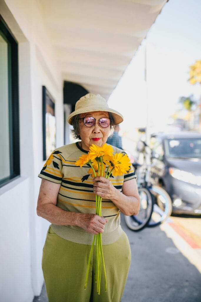elderly woman smelling some flowers