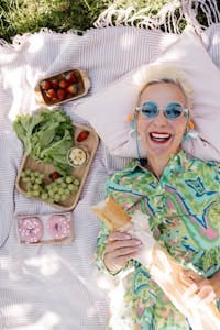Senior woman with pastries and salad at a sunny picnic, smiling joyfully. | The Mind-Preserving Diet: 6 Doctor-Approved Foods That Guard Against Alzheimer's & Cognitive Decline