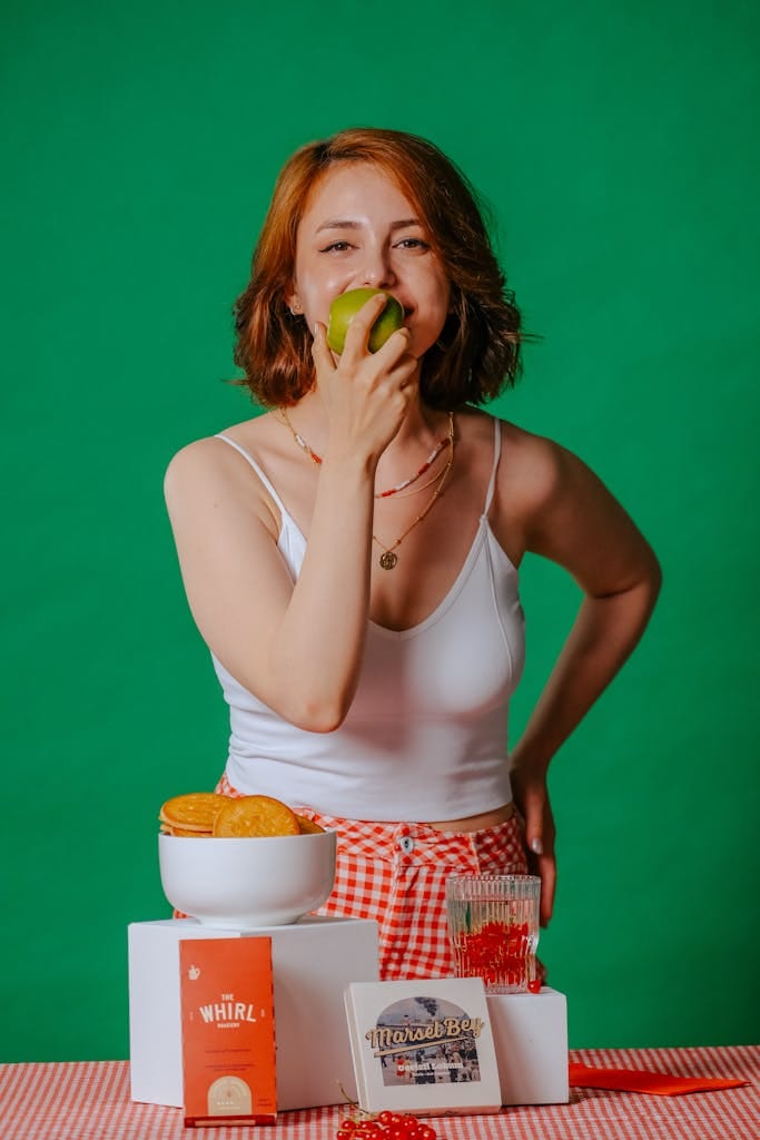 Smiling woman eating an apple, surrounded by vintage kitchen decor, creating a cheerful retro atmosphere. | Ozempic-Level Results? Unlock Your Body's OWN Fat-Burning Hormones By Eating Smarter (Science-Backed!)