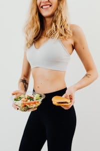 Smiling woman in sportswear balances healthy salad vs junk food choice. | Women Over 50 Are Obsessed: The "Big Mac Salad" Secret That Melts Belly Fat Fast!