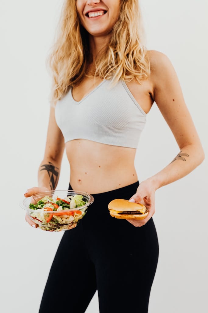 Smiling woman in sportswear balances healthy salad vs junk food choice. | Women Over 50 Are Obsessed: The "Big Mac Salad" Secret That Melts Belly Fat Fast!