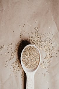 Top view of organic quinoa seeds in a wooden spoon on brown paper. | Muscle Breakthrough: I Quadrupled My Gains With This Super Grain (No More Protein Shakes!)
