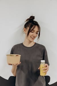 Woman holding a healthy meal bowl and juice, promoting nutritious lifestyle indoors. | daily metamucil
