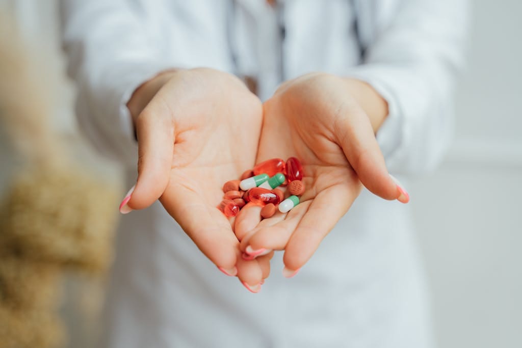 A close-up image of female hands holding diverse colorful pills and capsules. | Doctors Reveal: The 5 Powerhouse Vitamin Combos You NEED for Optimal Health