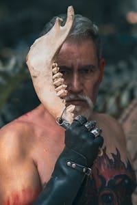 A shirtless elderly man holding an animal bone in a dramatic outdoor setting. | Fight Muscle Loss: The Top Foods Every Older Adult Needs for Lasting Strength.