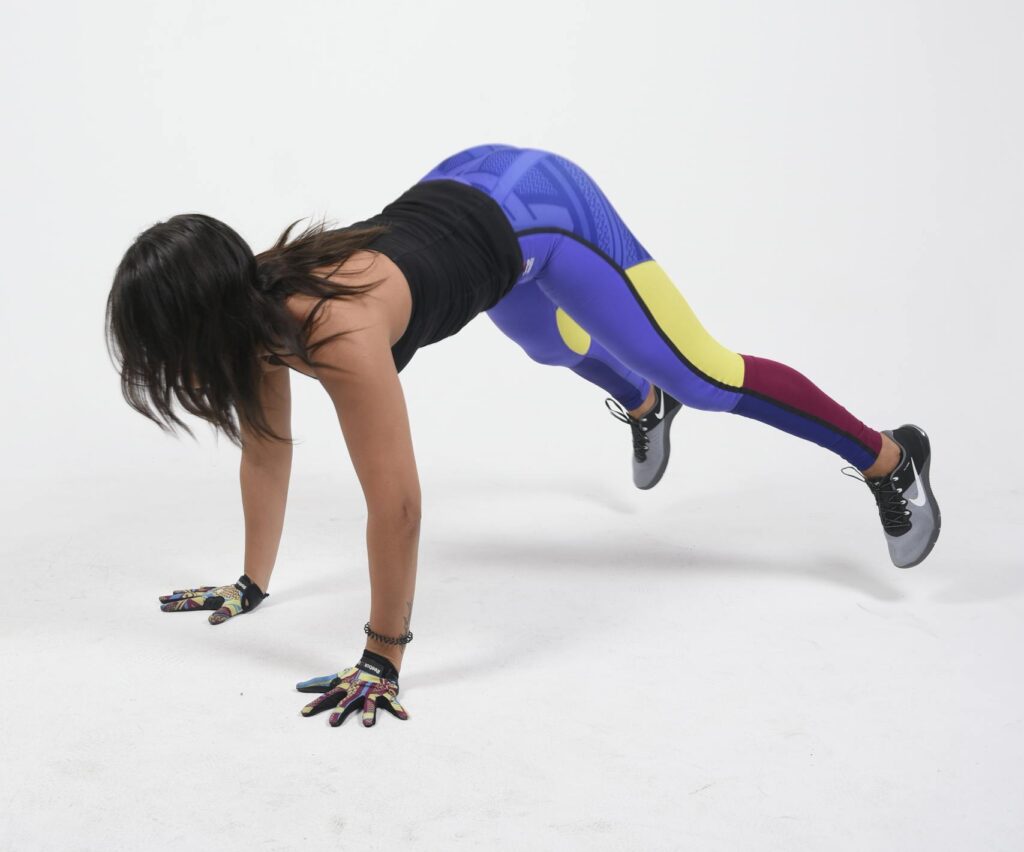 A woman in colorful sportswear doing a burpee exercise in a studio environment. | Torch Belly Fat After 40: 5 Moves That Crush a 30-Min Run for Core & Abs