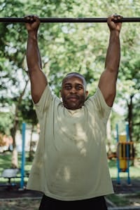 Adult man exercises on pull-up bar in a sunny outdoor park setting. | Men Over 45: Can You Pass These 5 Vital Strength & Longevity Tests?