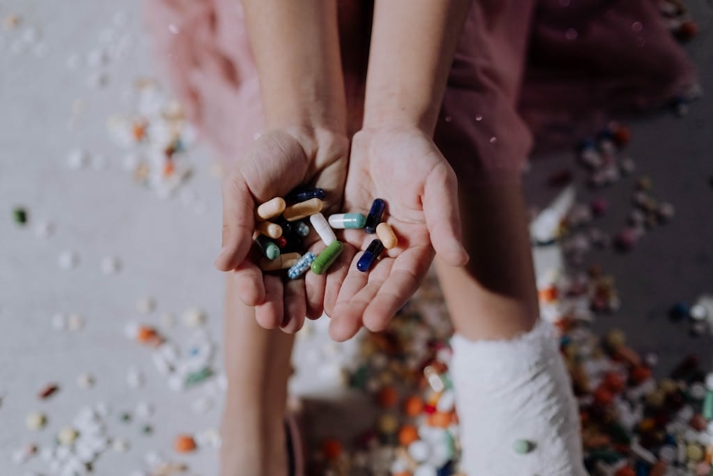 Close-up of a child holding pills with an injured leg in a cast, symbolizing health and recovery. | Tired, Swollen Legs? 8 Essential Vitamins to Recharge Your Leg Circulation
