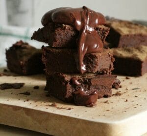 Delicious stack of chocolate brownies drizzled with gooey syrup on a wooden board. | Sweet & Guilt-Free: This High-Protein 2-Ingredient Fudge Delivers Pure Protein Power!