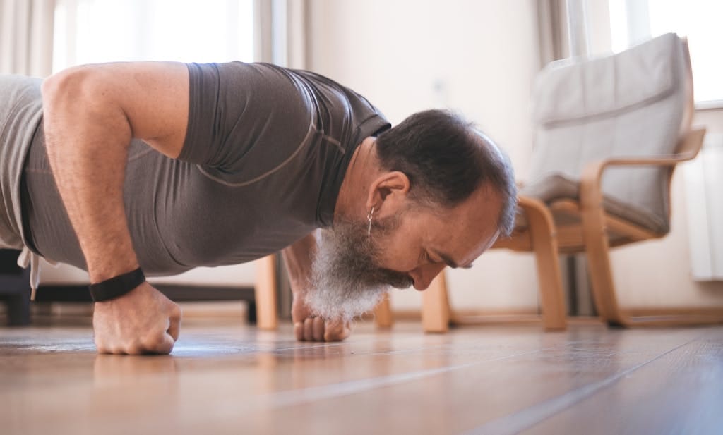 Elderly man exercising indoors with push-ups on a wooden floor for fitness. | Aged 60+? This ONE Workout Can TRULY Transform Your Body & Life