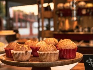 Delicious muffins displayed on a cakestand in a cozy kitchen setting. | High-Protein Cinnamon Roll Muffins