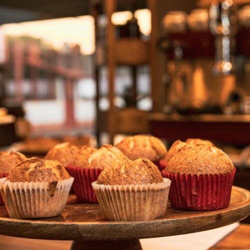 Delicious muffins displayed on a cakestand in a cozy kitchen setting. | High-Protein Cinnamon Roll Muffins