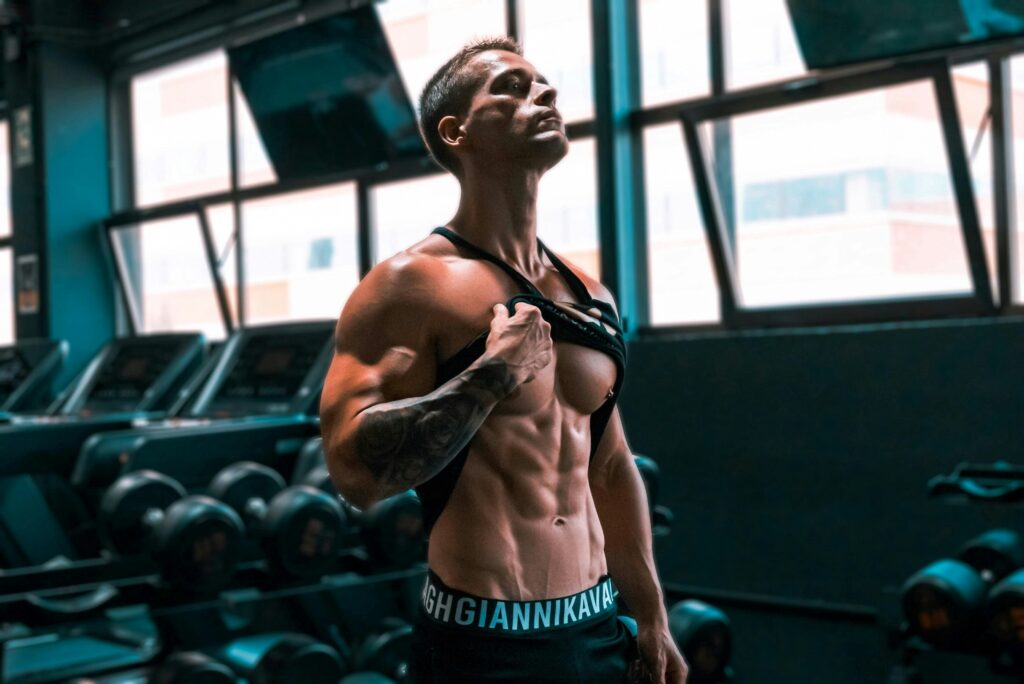 Muscular man showing abs and tattoos in a gym setting. | Sculpt Your Six-Pack at Home: Just 10 Minutes, Zero Equipment Needed!