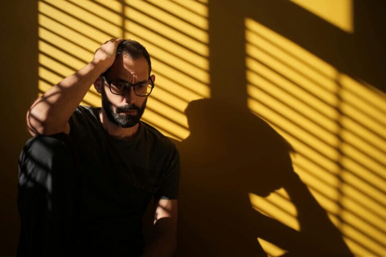 Contemplative man with dramatic shadows, moody indoor scene. | Don’t Miss These 5 Subtle Mini Stroke Symptoms (They Could Save Your Life)