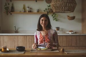 A woman smiles while preparing food in a warm and inviting kitchen setting. | The Gut Health Game-Changer? This Obscure Fiber Feeds Your Good Bacteria Like Nothing Else