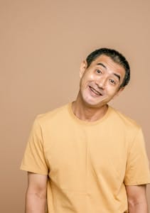 Smiling elderly man wearing a yellow t-shirt against a brown background. | Defy Your Age: Japanese Men's Strict Routines That Made One Look Younger Than a Decade Ago