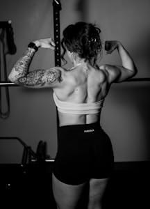 Strong muscular woman flexing in gym, showcasing tattoos and fitness dedication. | Trainer Reveals: The 3 Muscles You're Skipping (And Why Your Progress Is Stuck)