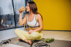 woman eating a burger and salad | I Asked 4 Dietitians How They 'Cheat' on a Diet for Weight Loss (My Cravings Just Vanished!)