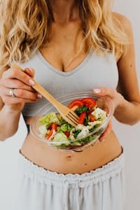 Woman in sports bra enjoying a fresh vegetable salad for a healthy lifestyle. | Shred Fat Faster: 7 Vegan Diet Hacks That OUTPERFORM Keto for Rapid Weight Loss