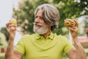 elderly man choosing between an apple and a burger | 10 Anti-Aging Superfoods That Could Add Years to Your Life (Science Says So)