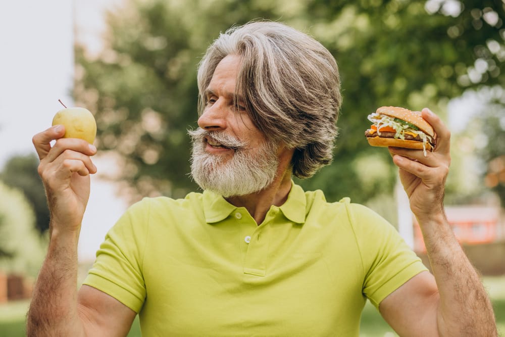 elderly man choosing between an apple and a burger | 10 Anti-Aging Superfoods That Could Add Years to Your Life (Science Says So)