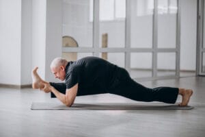 flexible older man practicing yoga in the gym | Why These Baby Boomers Are More Ripped Than Gen Z—Their Anti-Aging Routine Will Blow Your Mind